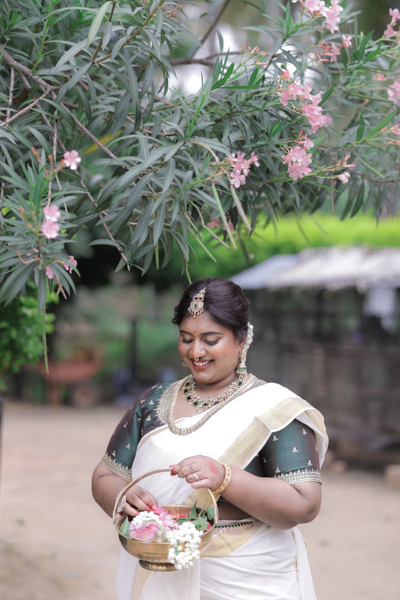 Dr. Ashvini Sundararaju under a pink oleander tree in a Kasavu saree