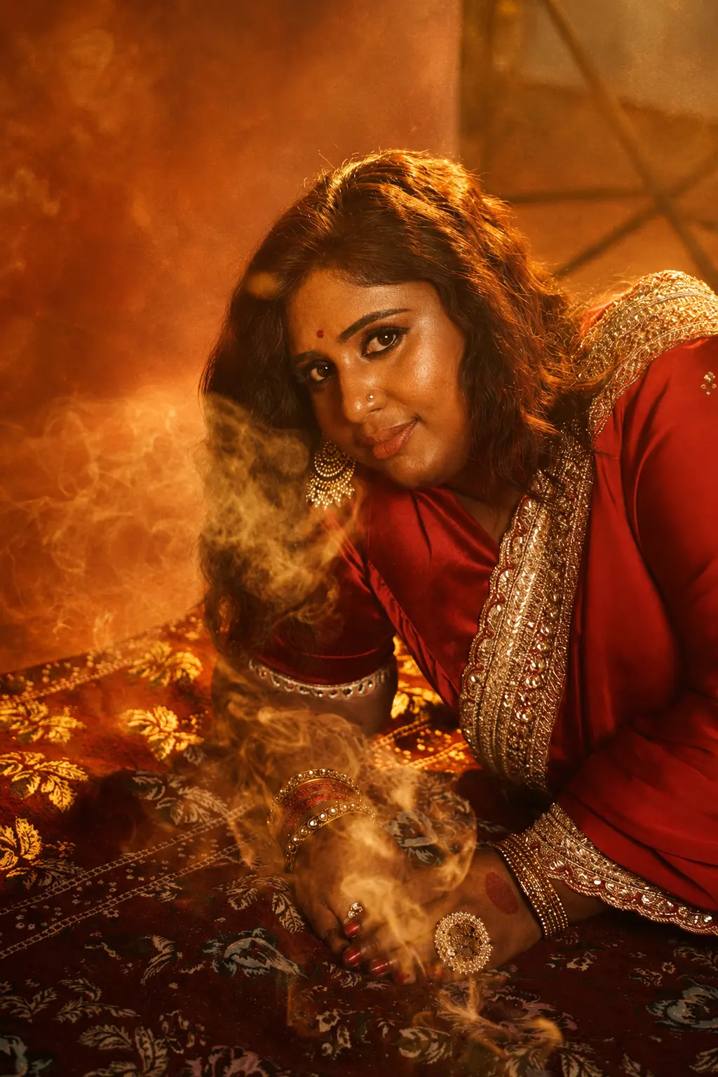 Dr. Ashvini Sundararaju in a red saree amid golden smoke