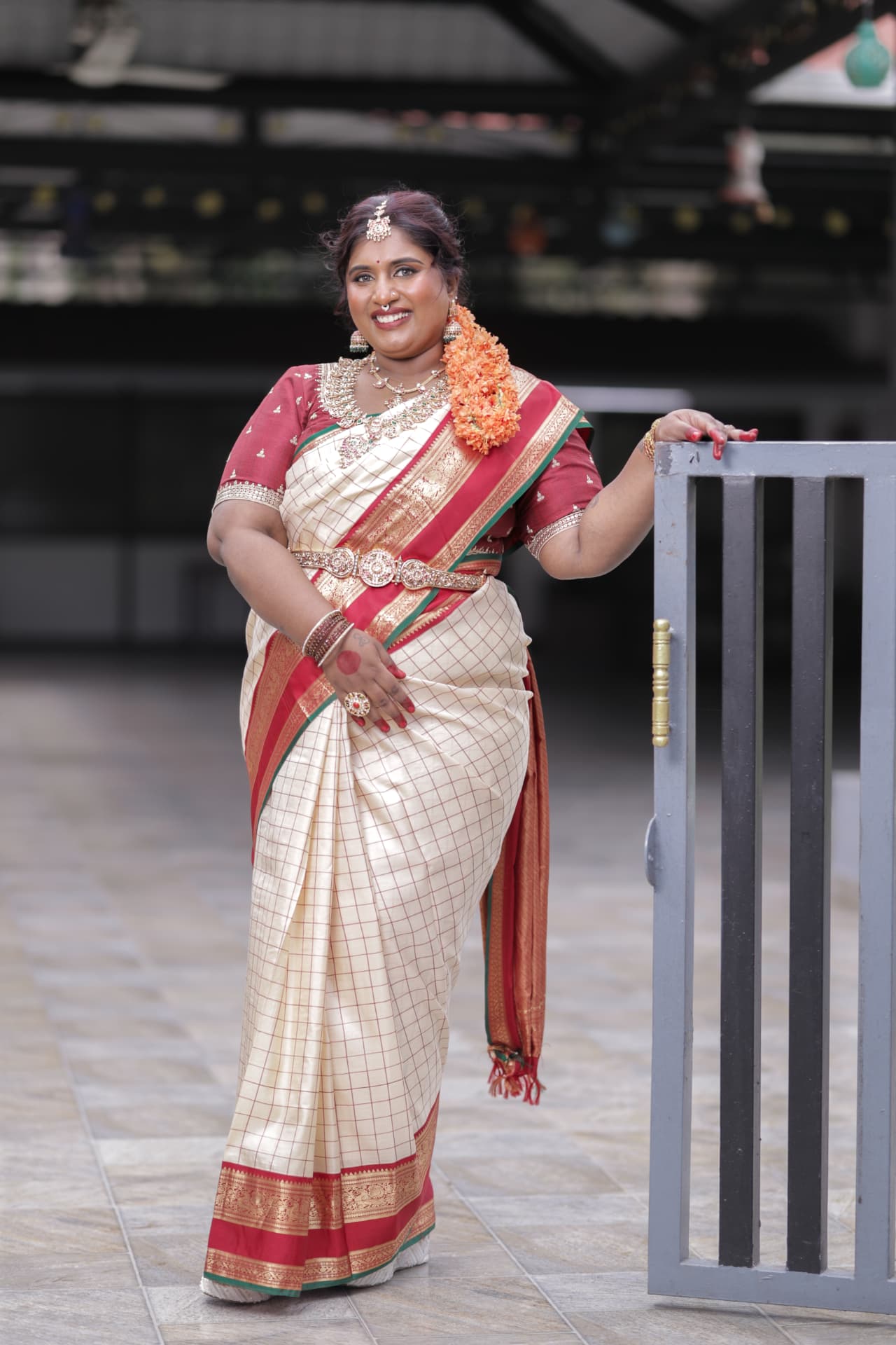 Dr. Ashvini Sundararaju posing by a gate in a cream saree