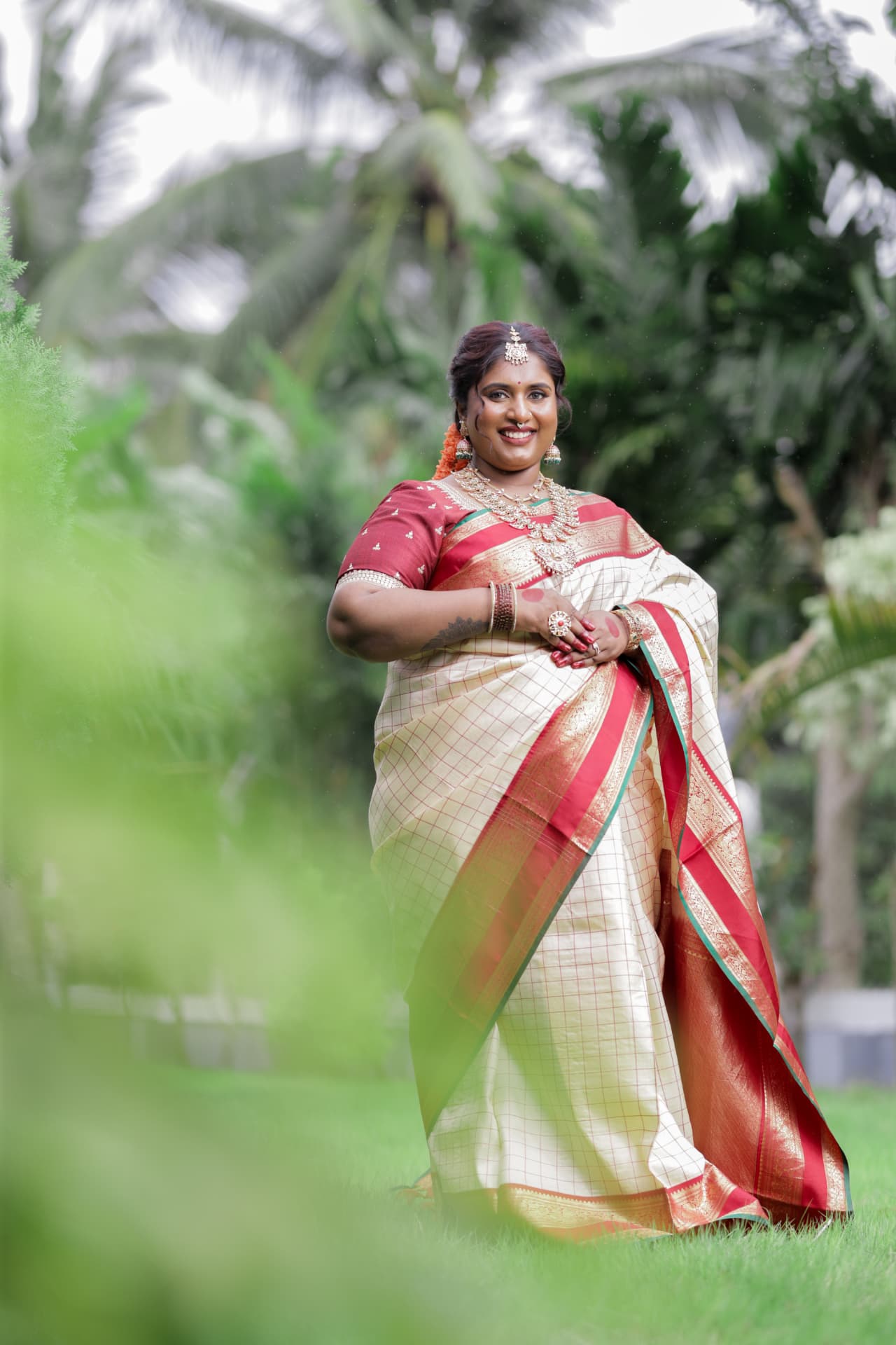 Dr. Ashvini Sundararaju in a cream saree with palm trees behind her