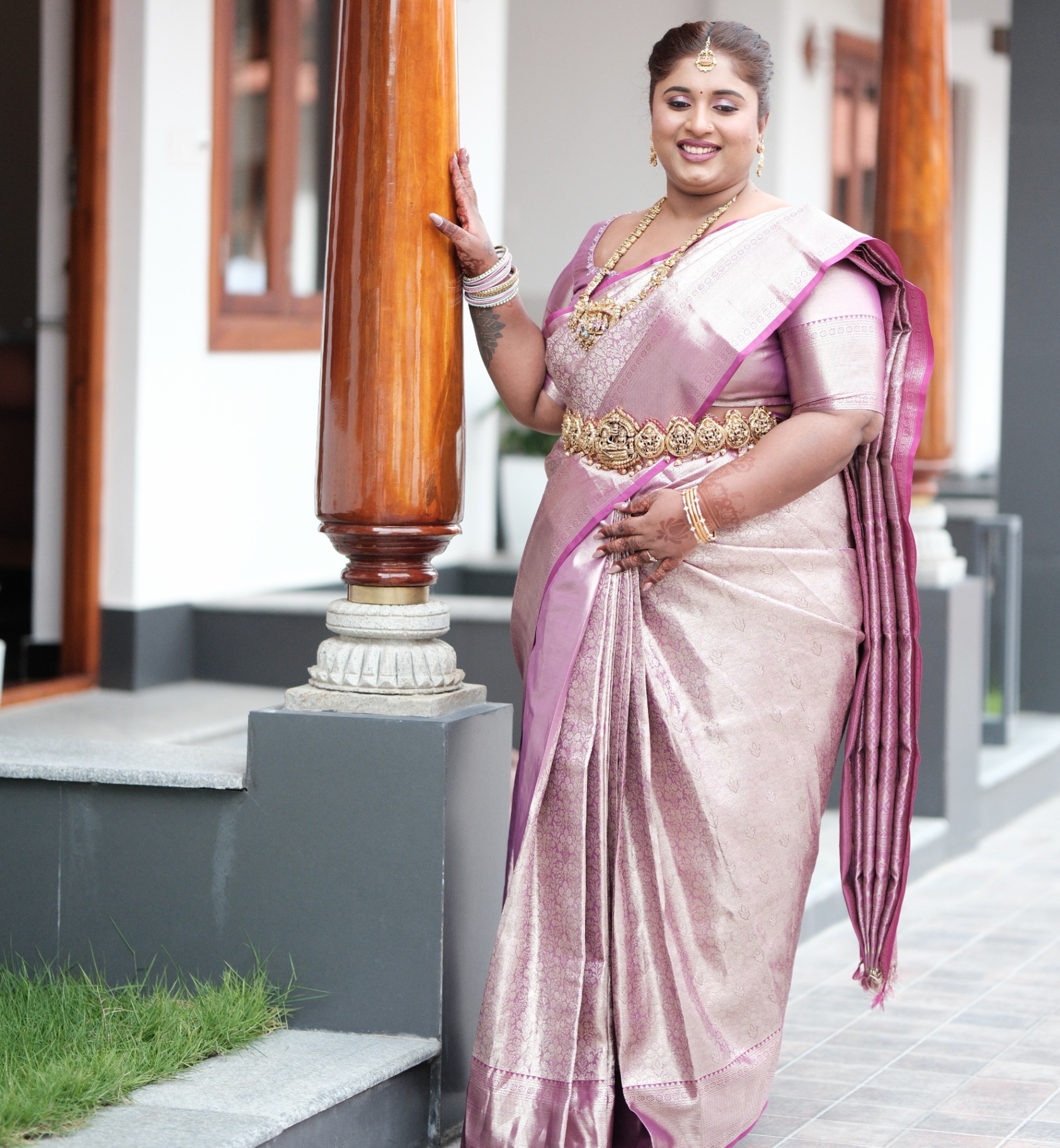 Dr. Ashvini Sundararaju leaning against a pillar in a lilac Kanjeevaram saree