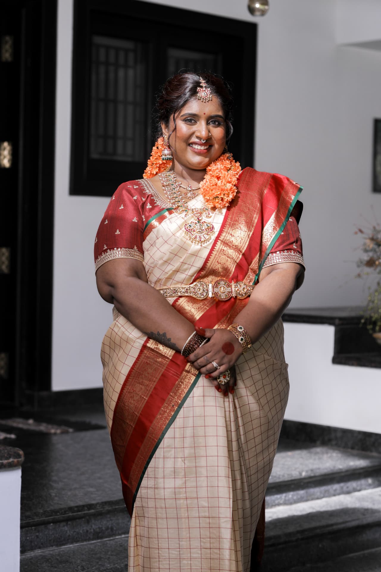 Dr. Ashvini Sundararaju standing by white steps in a cream saree
