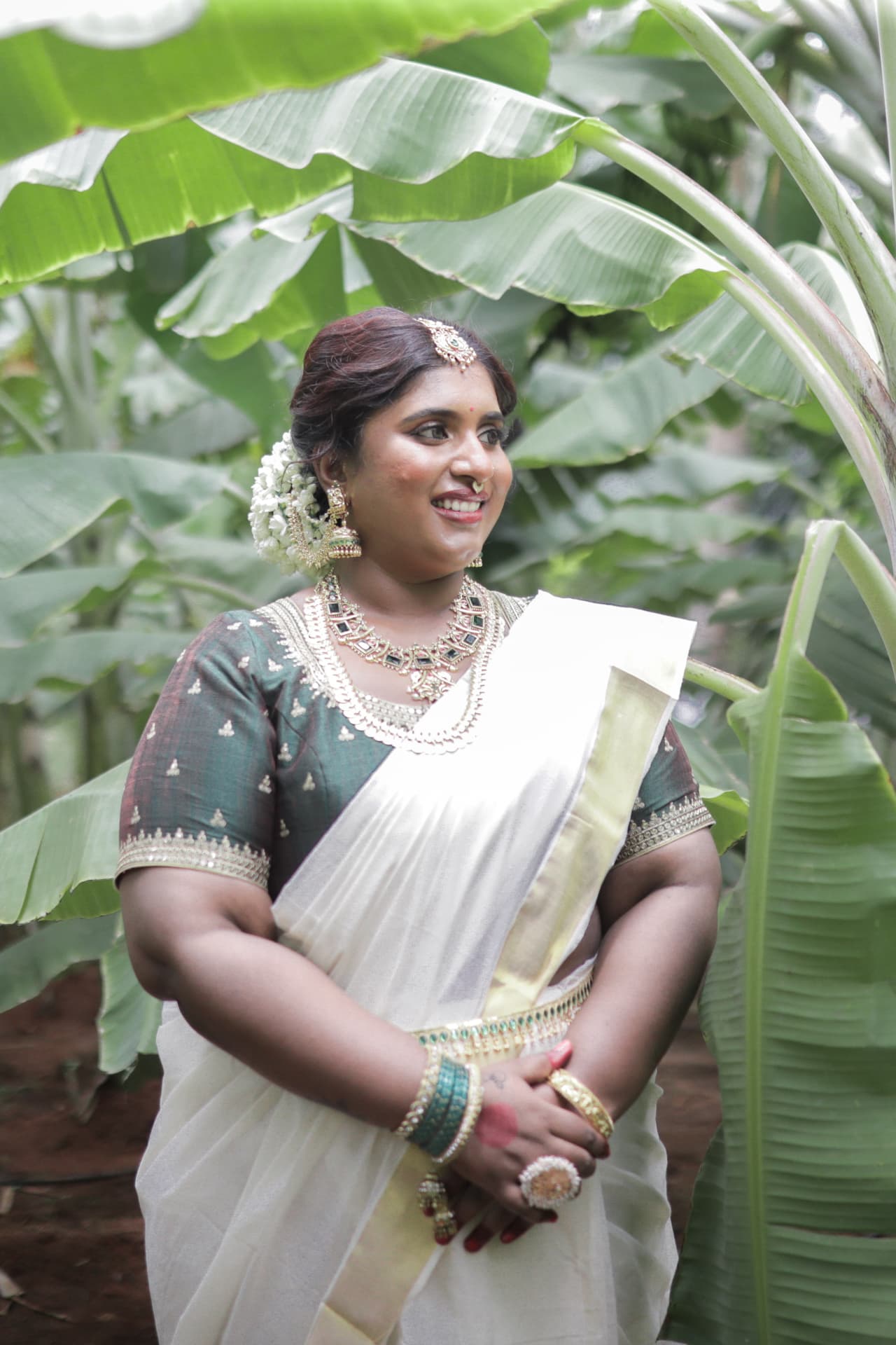 Dr. Ashvini Sundararaju standing in a banana grove in a Kasavu saree